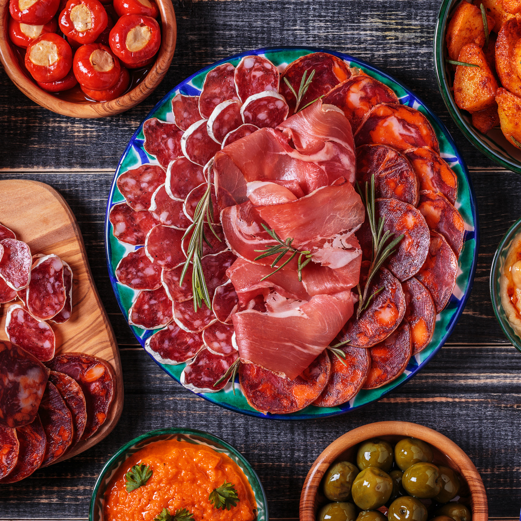 Большая тарелка с мясной нарезкой в центре праздничного стола