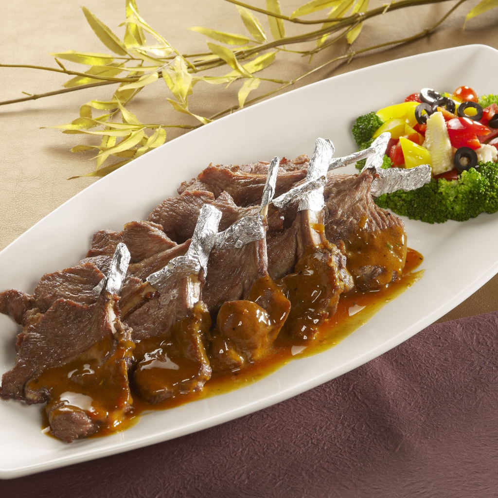 Мясо на белой тарелке с соусом и овощами 