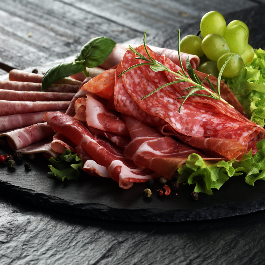 Мясная нарезка с листьями салата и белым виноградом 