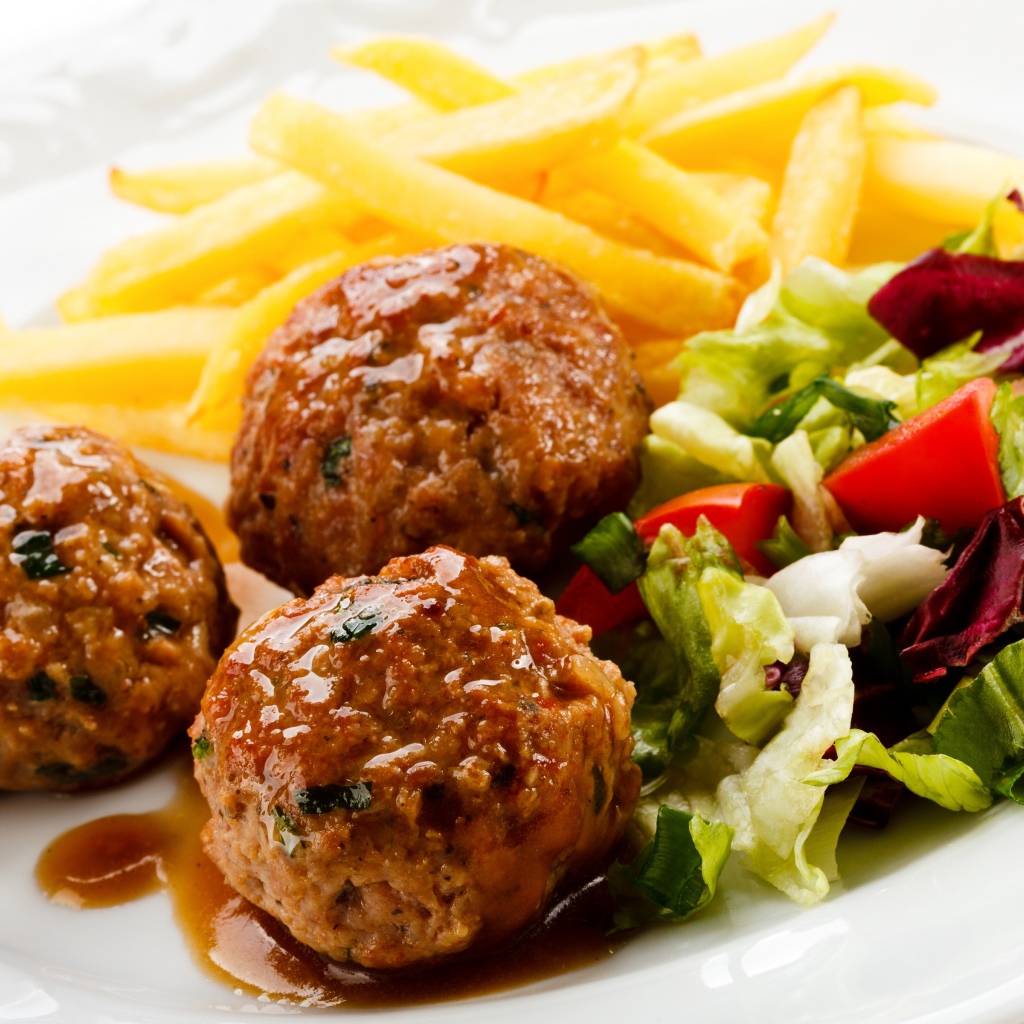 Тефтели с картофелем фри и салатом на белой тарелке 