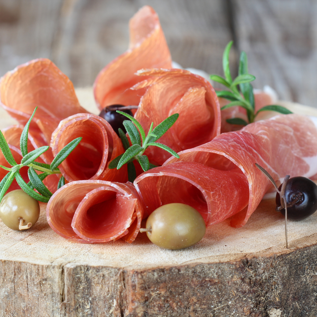 Прошутто  с оливками на деревянном столе 