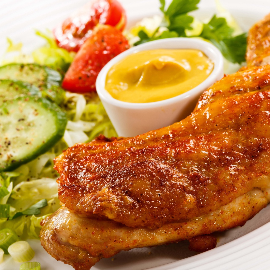 Жареная куриная ножка с овощами и соусом на тарелке