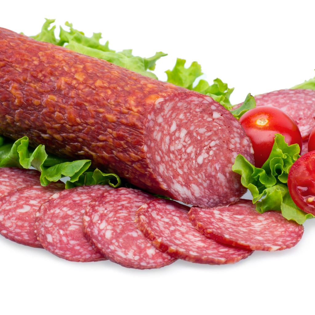 Колбаса с помидорами и зелеными листьями салата на белом фоне