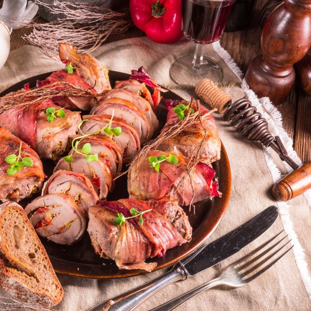 Нарезанные мясные рулеты на столе с хлебом