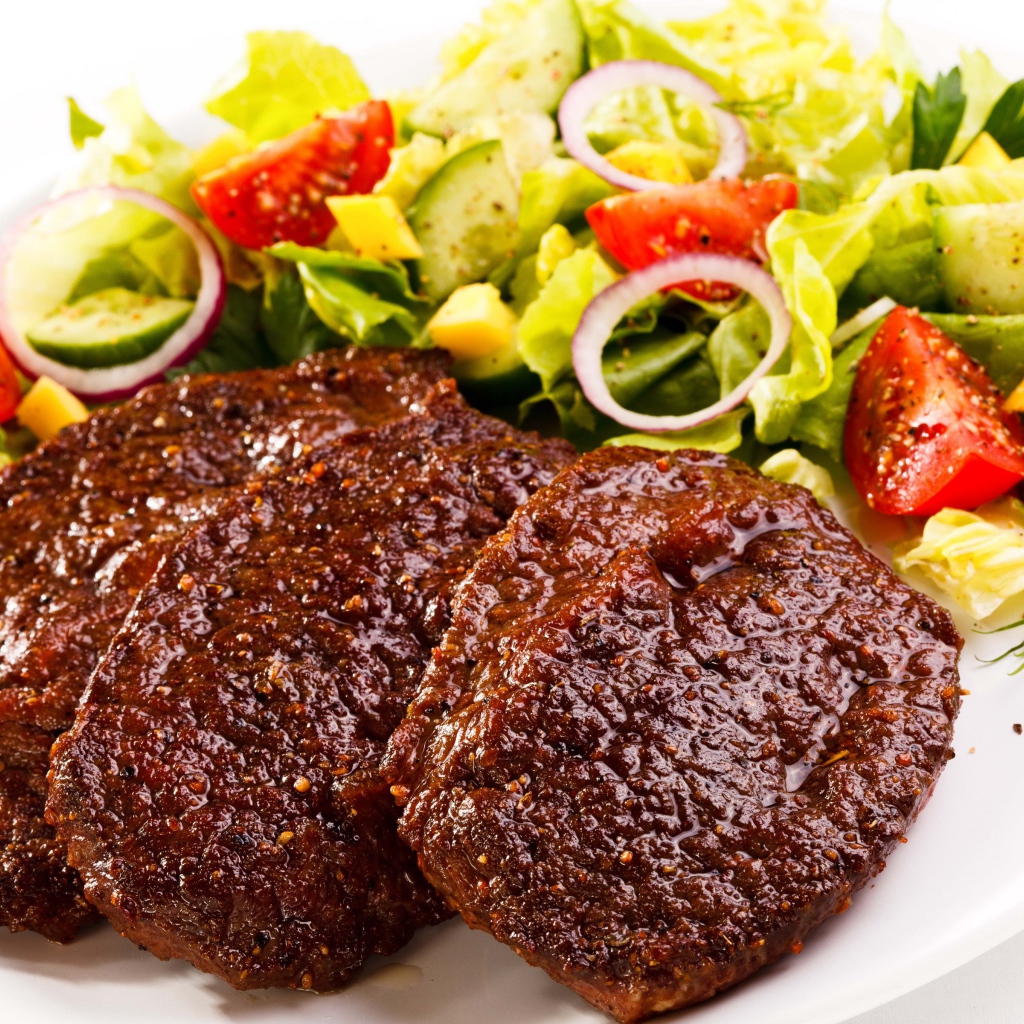 Три котлеты на тарелке с салатом на белом фоне