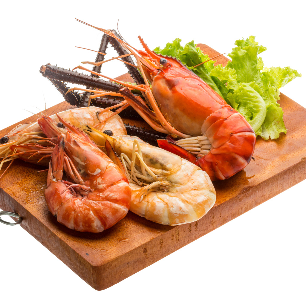 Вареные креветки с листьями салата на разделочной доске