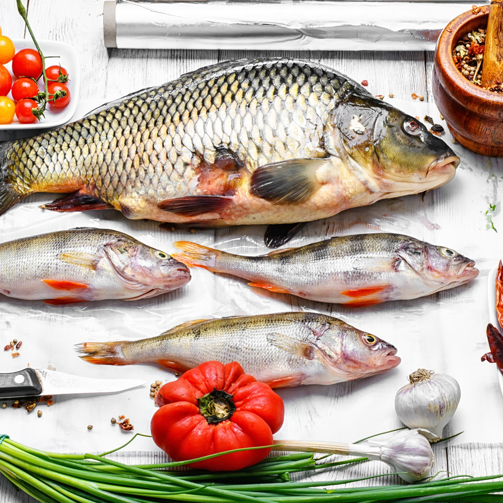 Свежая рыба на столе с помидорами, зеленым луком и  специями
