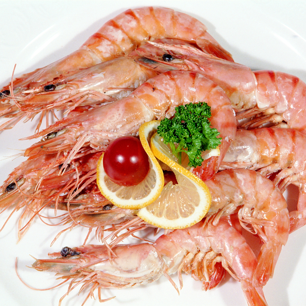 Креветки с лимоном и помидором на белой тарелке