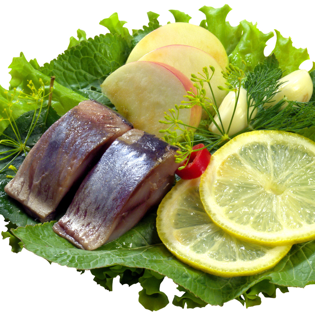 Кусочки сельди с кусочками яблока и лимона на белом фоне