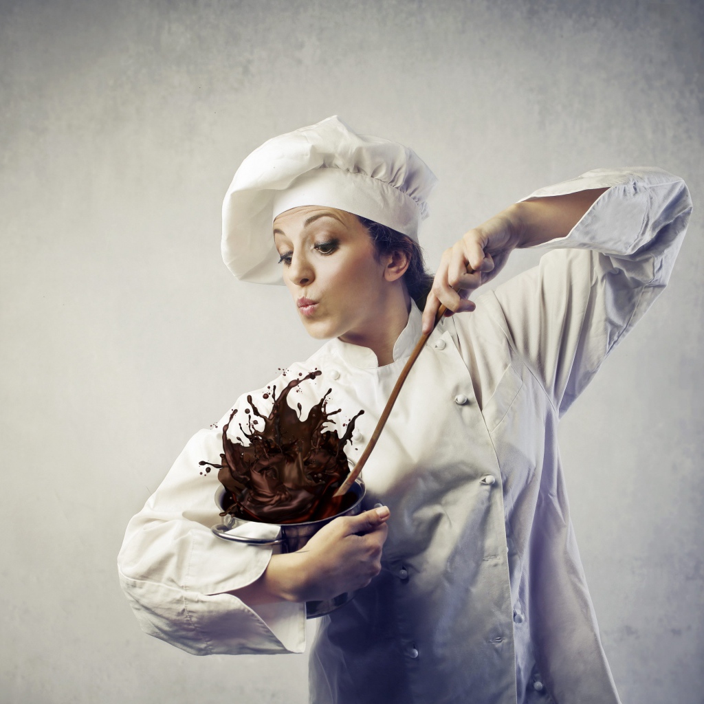 Женщина повар мешает шоколад в посуде на сером фоне