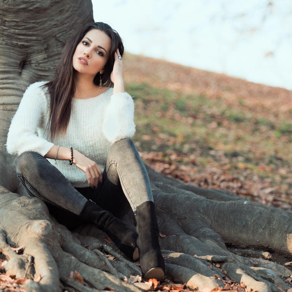 Красивая девушка сидит у дерева