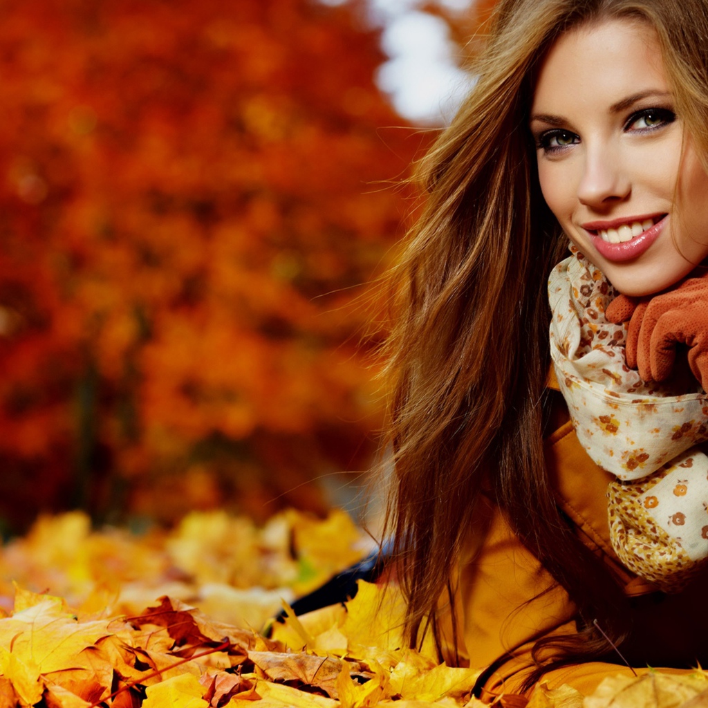 Красивая девушка лежит на опавших осенних листьях