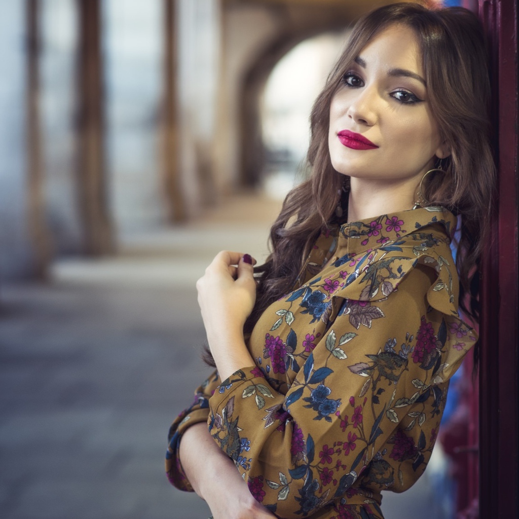 Девушка шатенка в красивом платье у стены