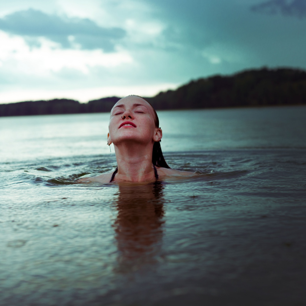 Молодая девушка купается в озере 