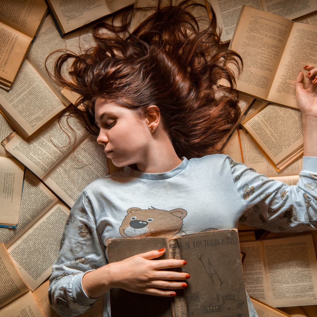 Молодая девушка спит на книгах