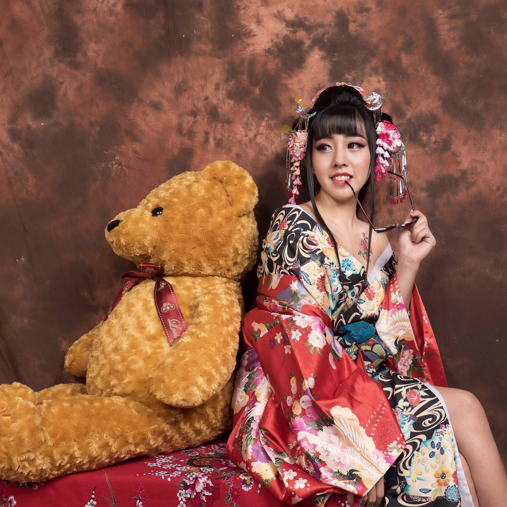 Девушка азиатка сидит с большим плюшевым медведем