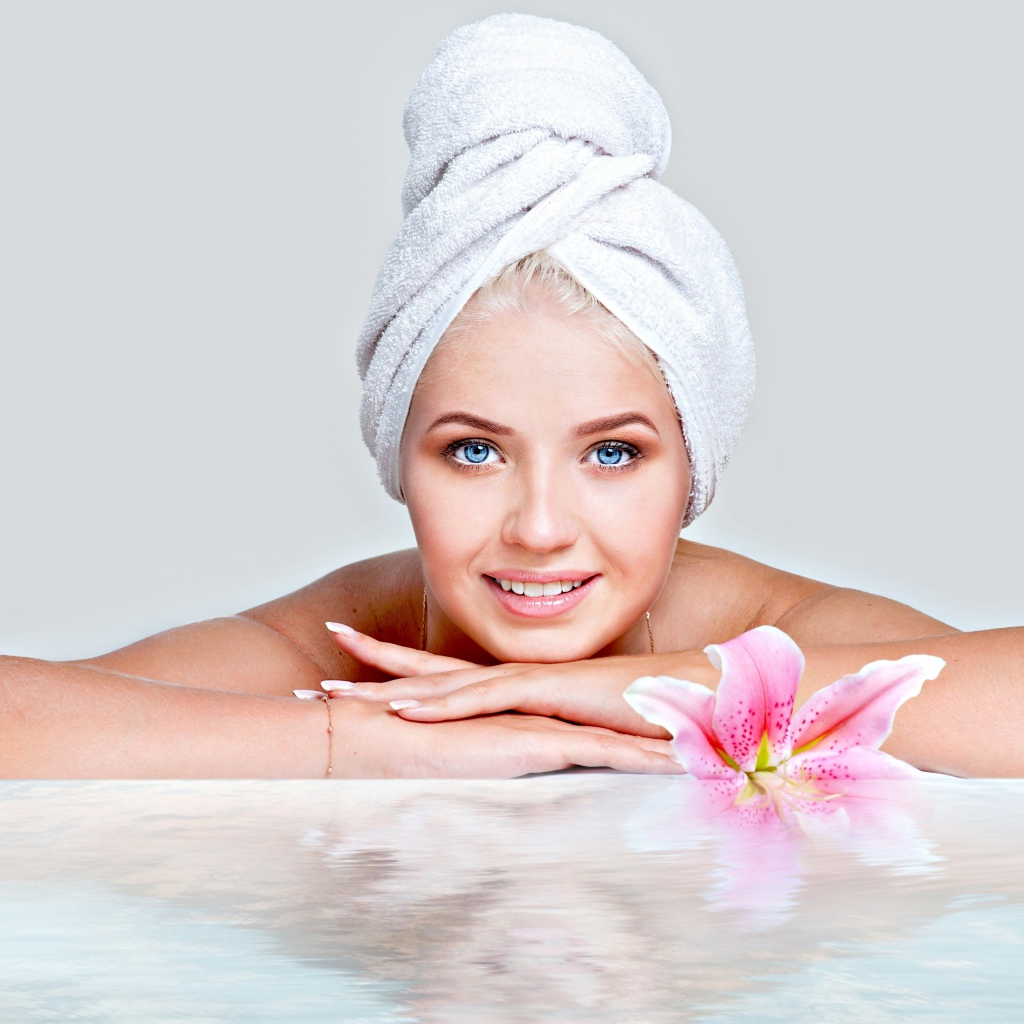 Красивая голубоглазая женщина в тюрбане с полотенца расслабляется в SPA