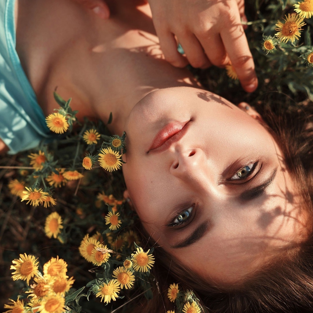 Красивая шатенка лежит на земле с желтыми цветами