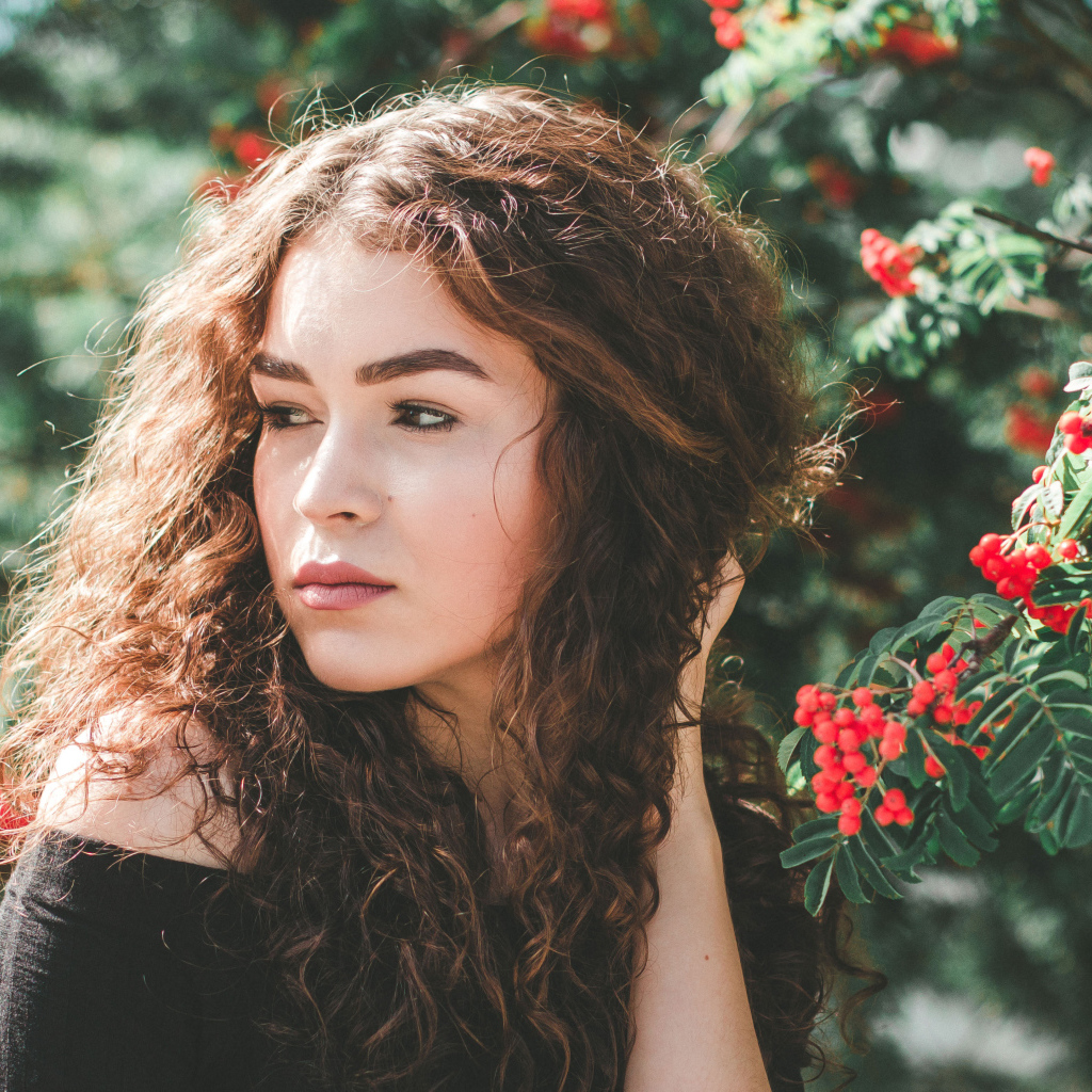 Красивая шатенка у ветки с красными ягодами рябины