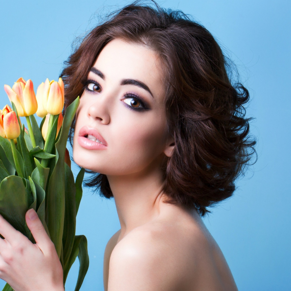 Красивая девушка брюнетка с букетом тюльпанов на голубом фоне