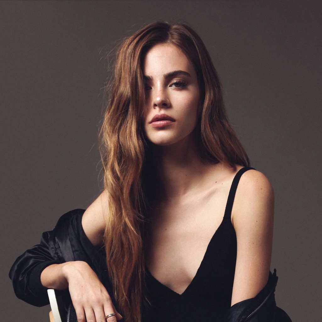 Красивая брюнетка в черном платье сидит на стуле