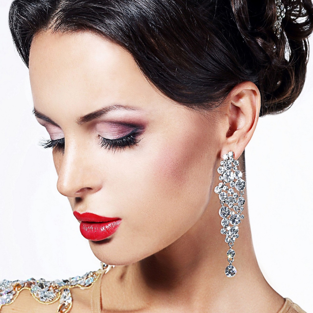 Красивая брюнетка в дорогих украшениях на белом фоне