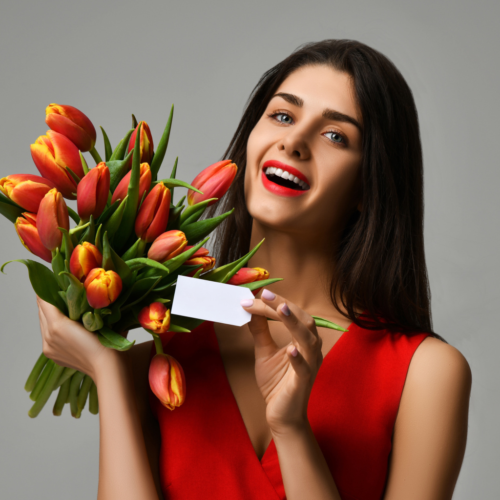 Красивая брюнетка с букетом тюльпанов на сером фоне