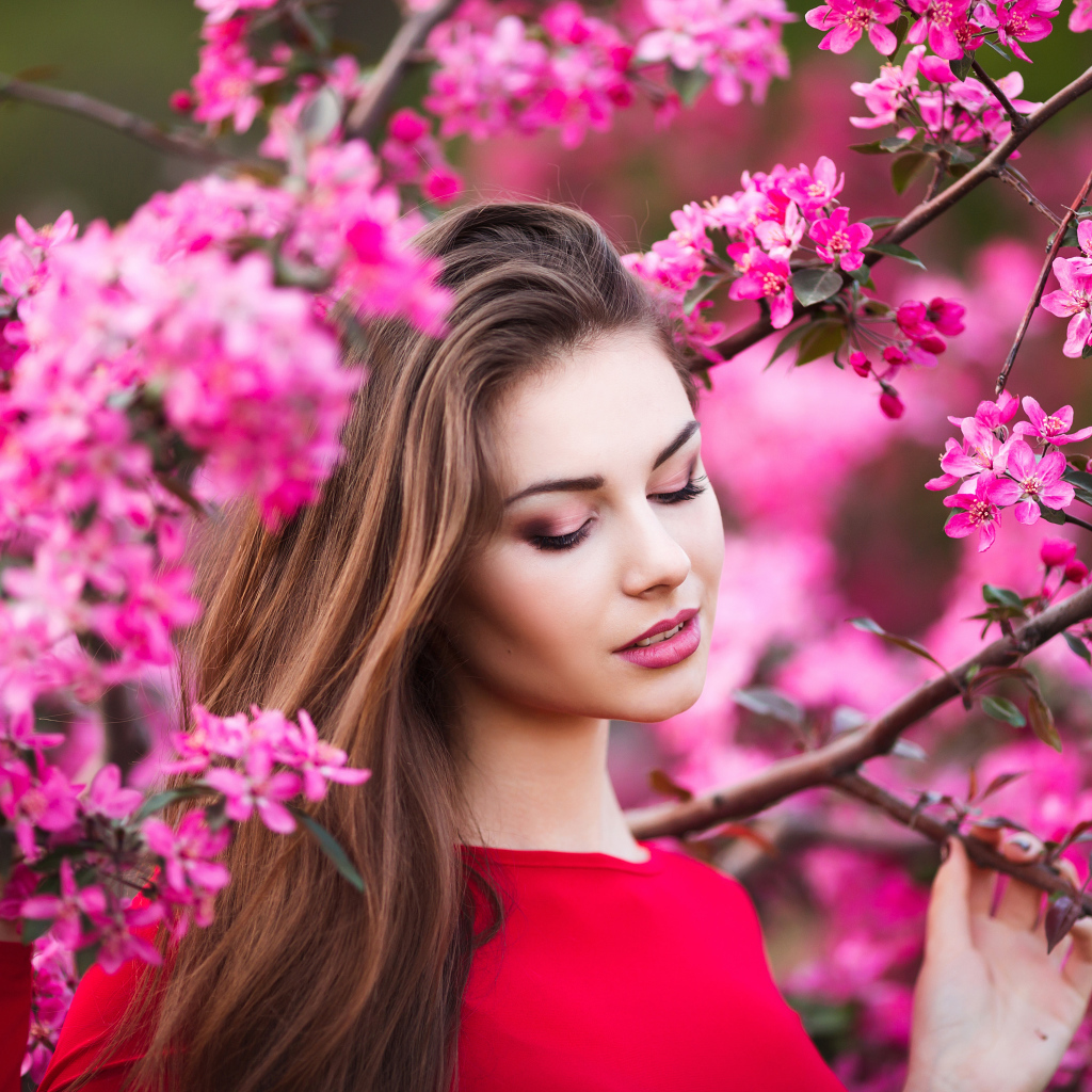 Красивая нежная шатенка у цветущей розовыми цветами ветки