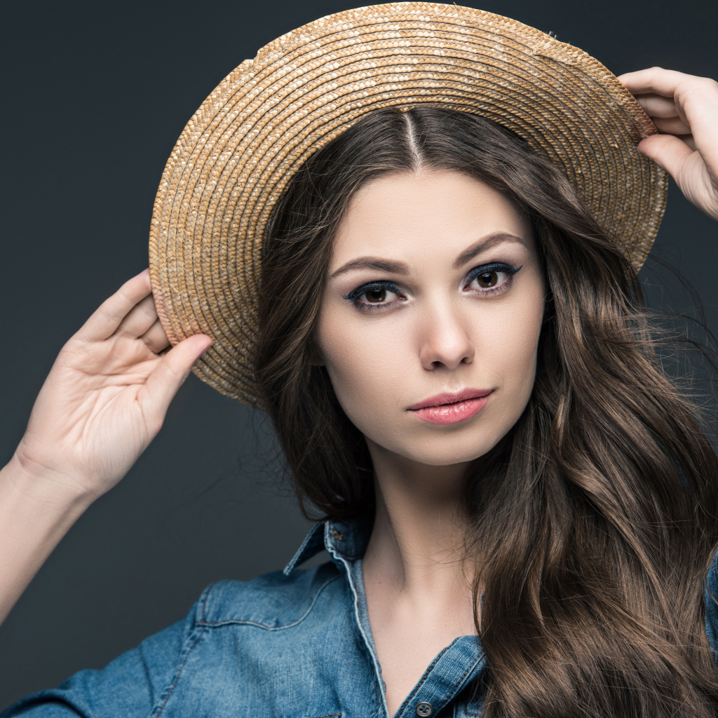 Красивая девушка в соломенной шляпе на сером фоне