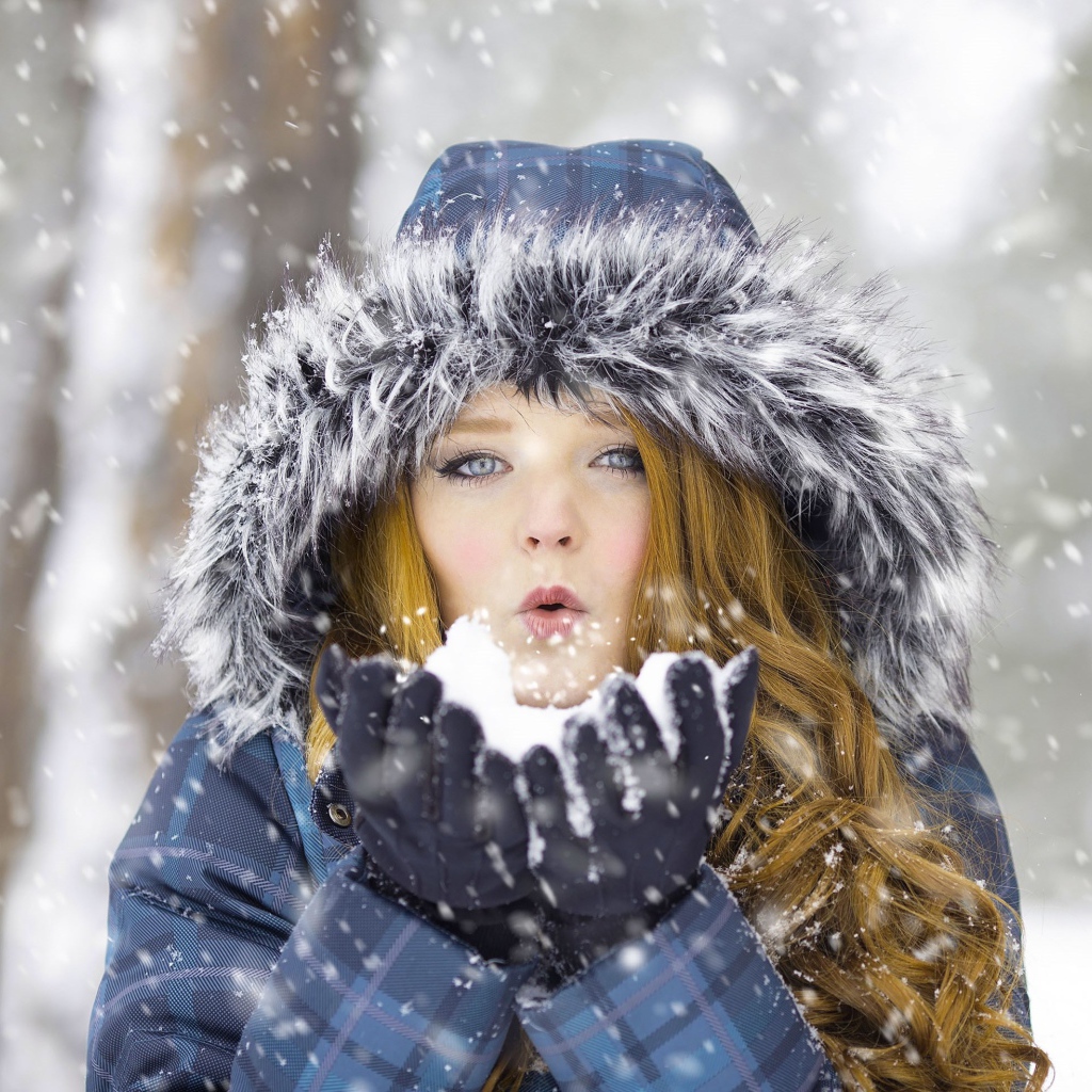 Красивая девушка в теплой куртке со снегом в руках