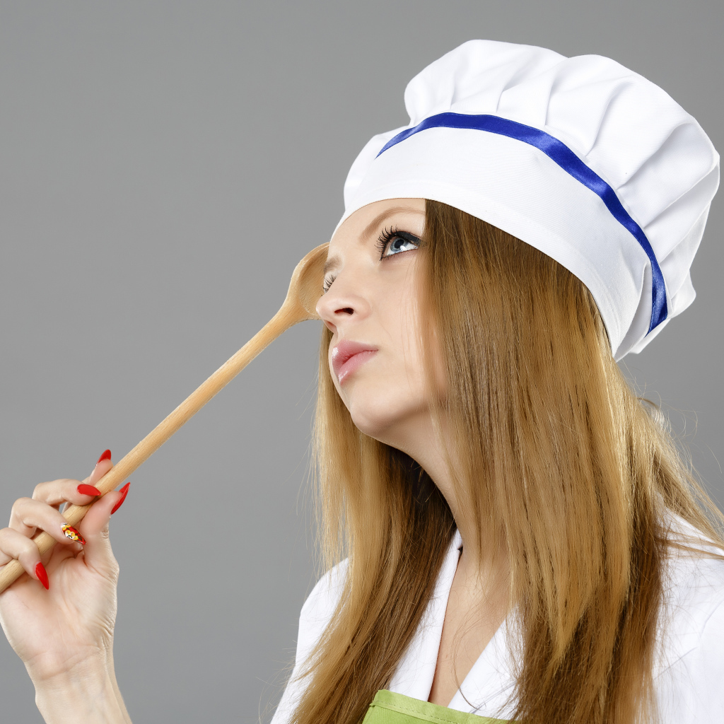 Красивая девушка в костюме повара на сером фоне