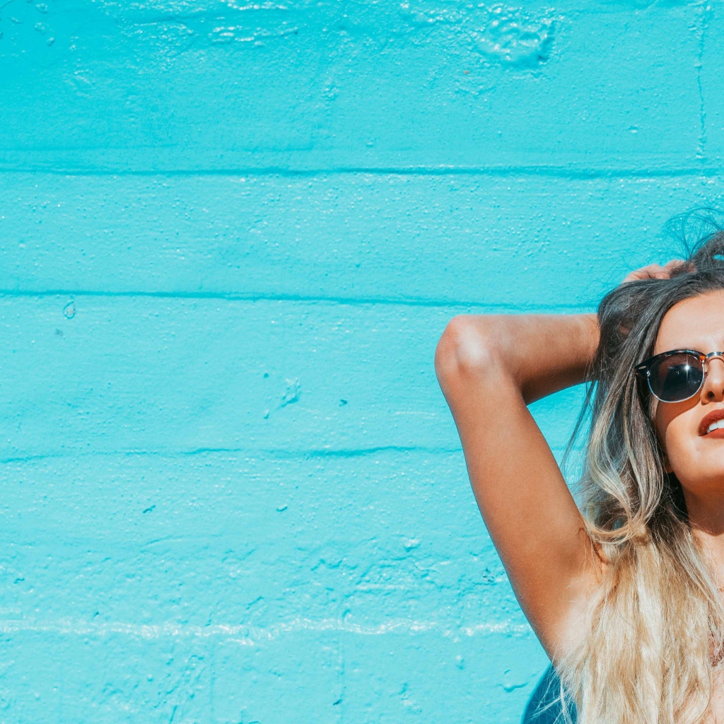 Красивая девушка в солнечных очках загорает на солнце летом