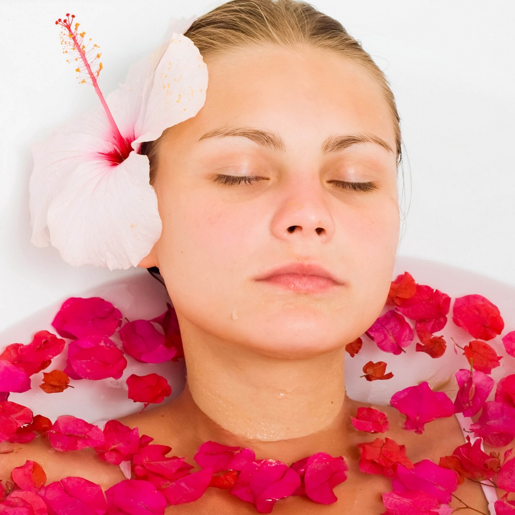 Красивая девушка в ванной с лепестками розы 