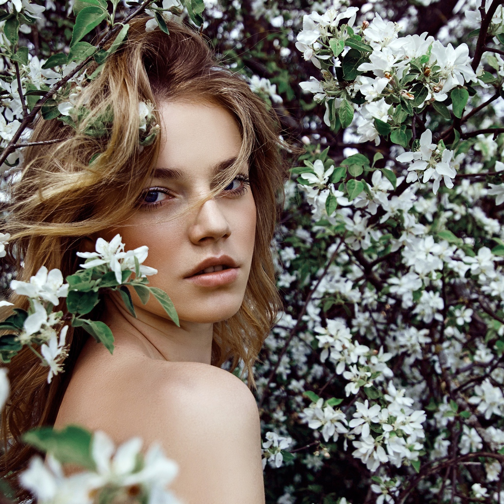 Красивая девушка в ветках цветущей яблони 