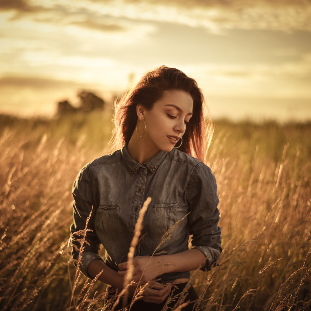 Красивая девушка на поле с колосками на фоне солнца