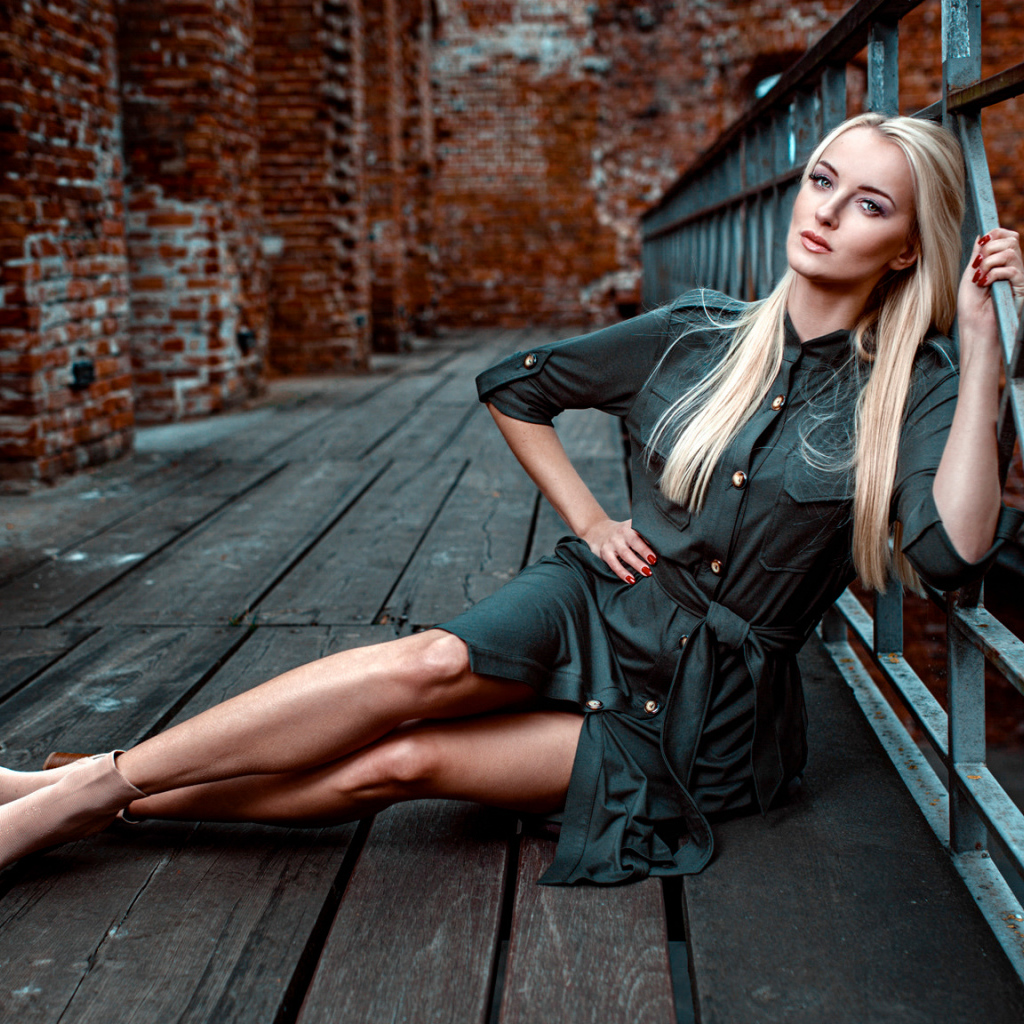 Красивая девушка сидит на деревянном полу