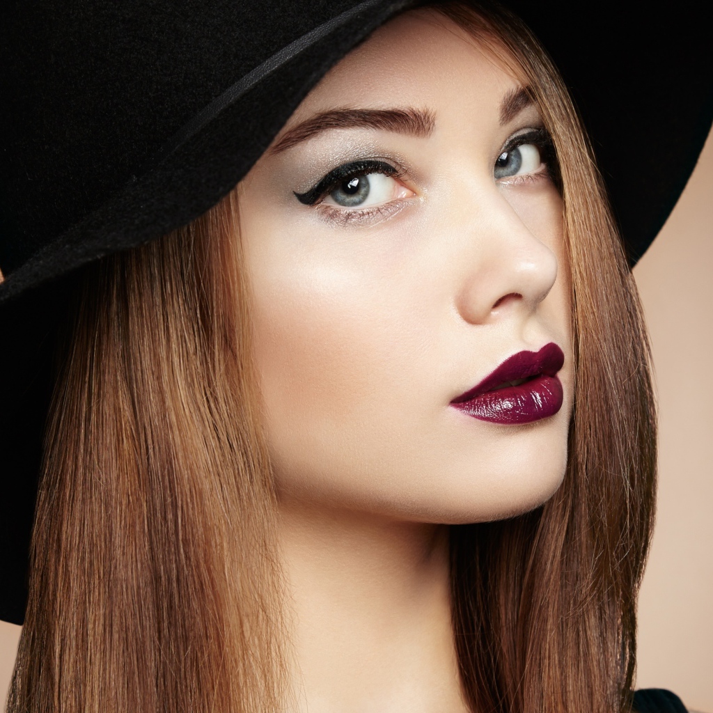 Красивая девушка с ярким макияжем в большой черной шляпе