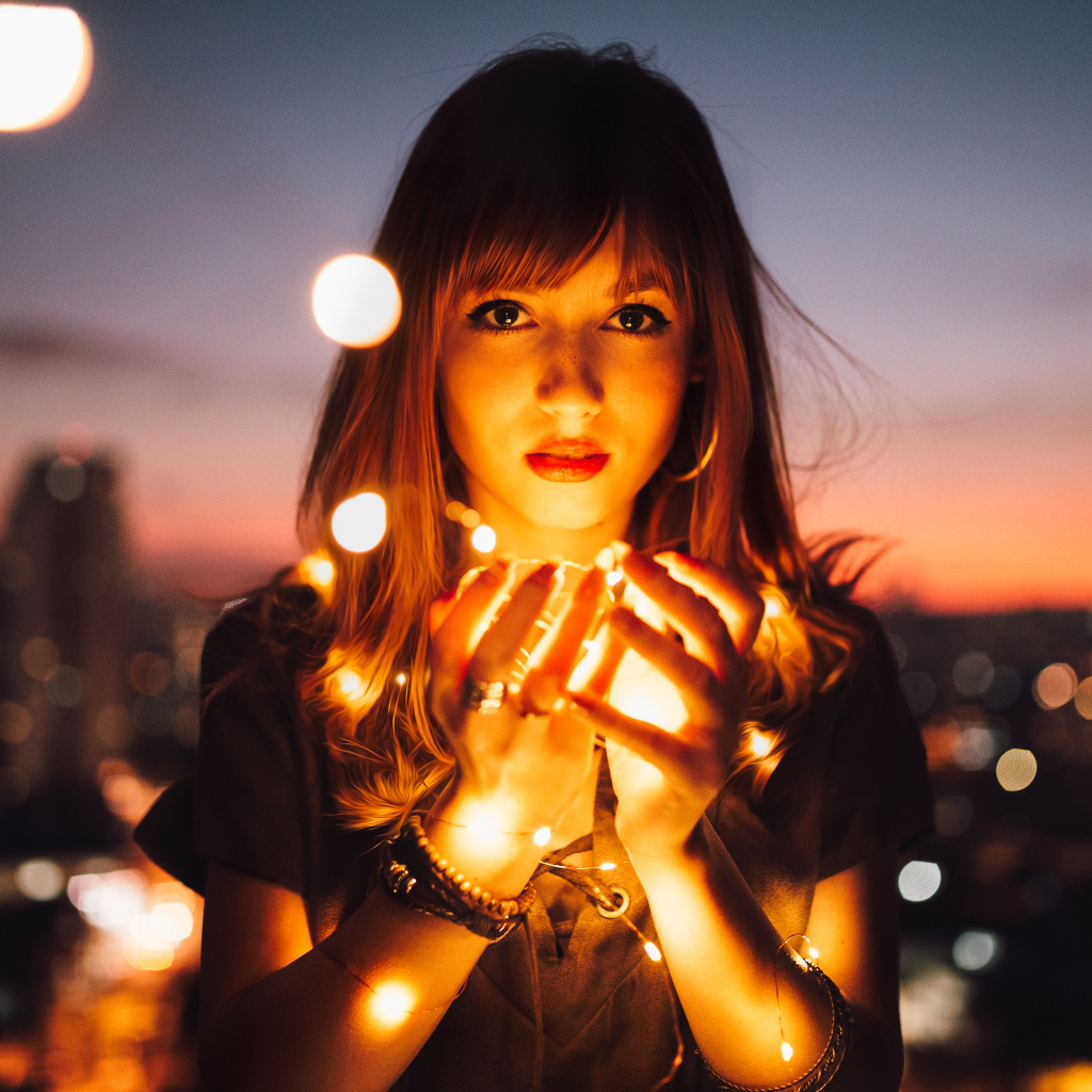 Красивая девушка с включенной гирляндой в руках 