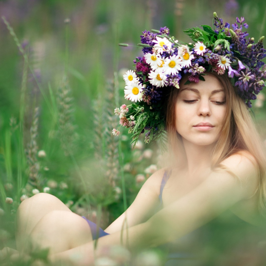Красивая девушка с венком из полевых цветов на голове летом 
