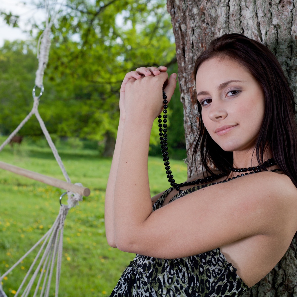 Красивая девушка с черными бусами под деревом