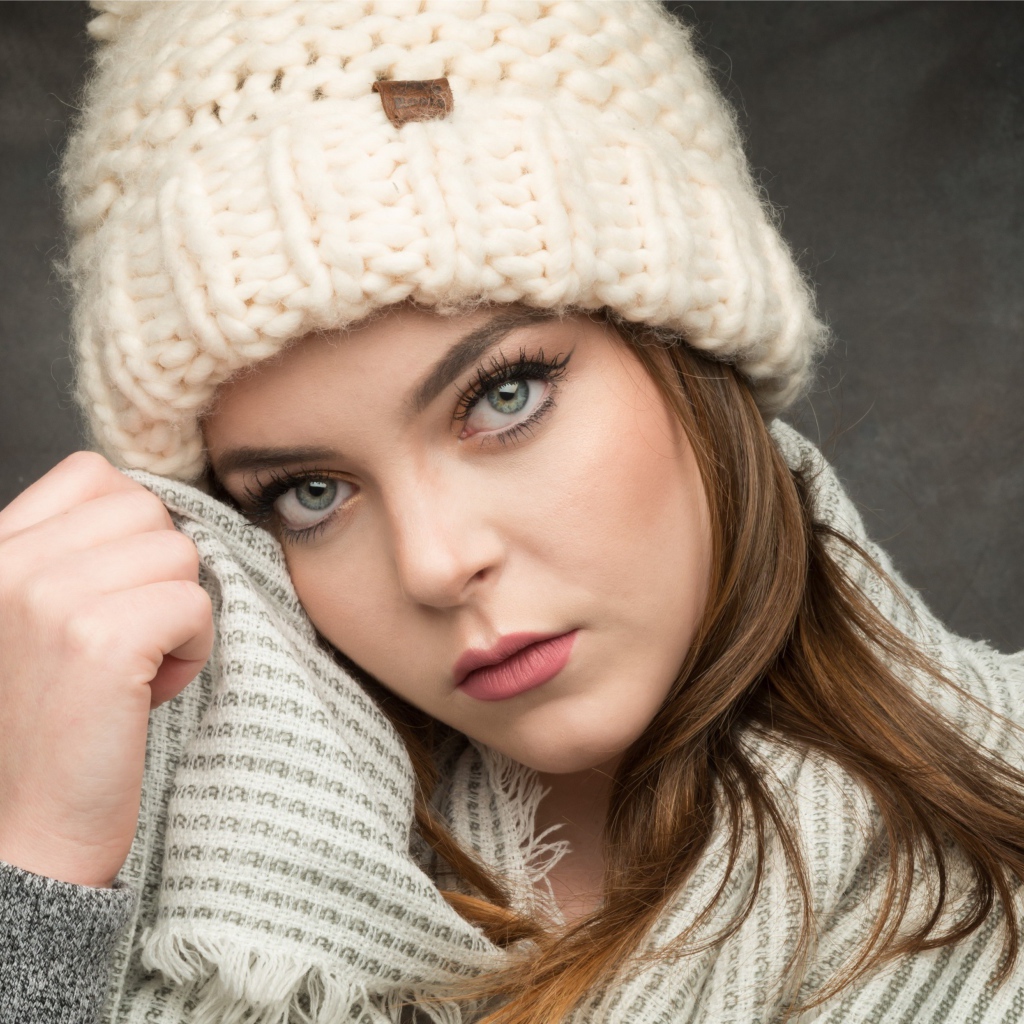 Красивая зеленоглазая девушка в белой вязаной шапке с шарфом