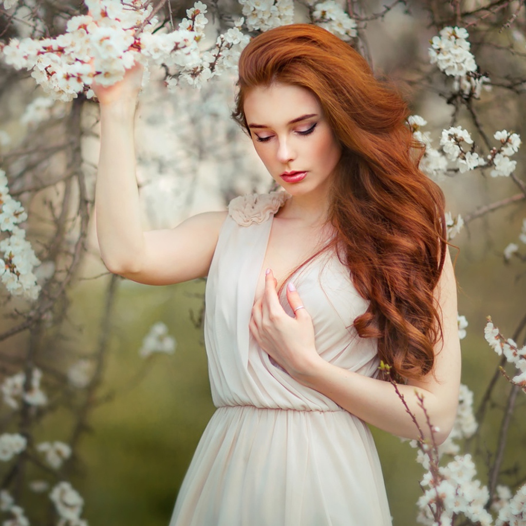 Красивая рыжеволосая девушка у цветущего дерева абрикоса 
