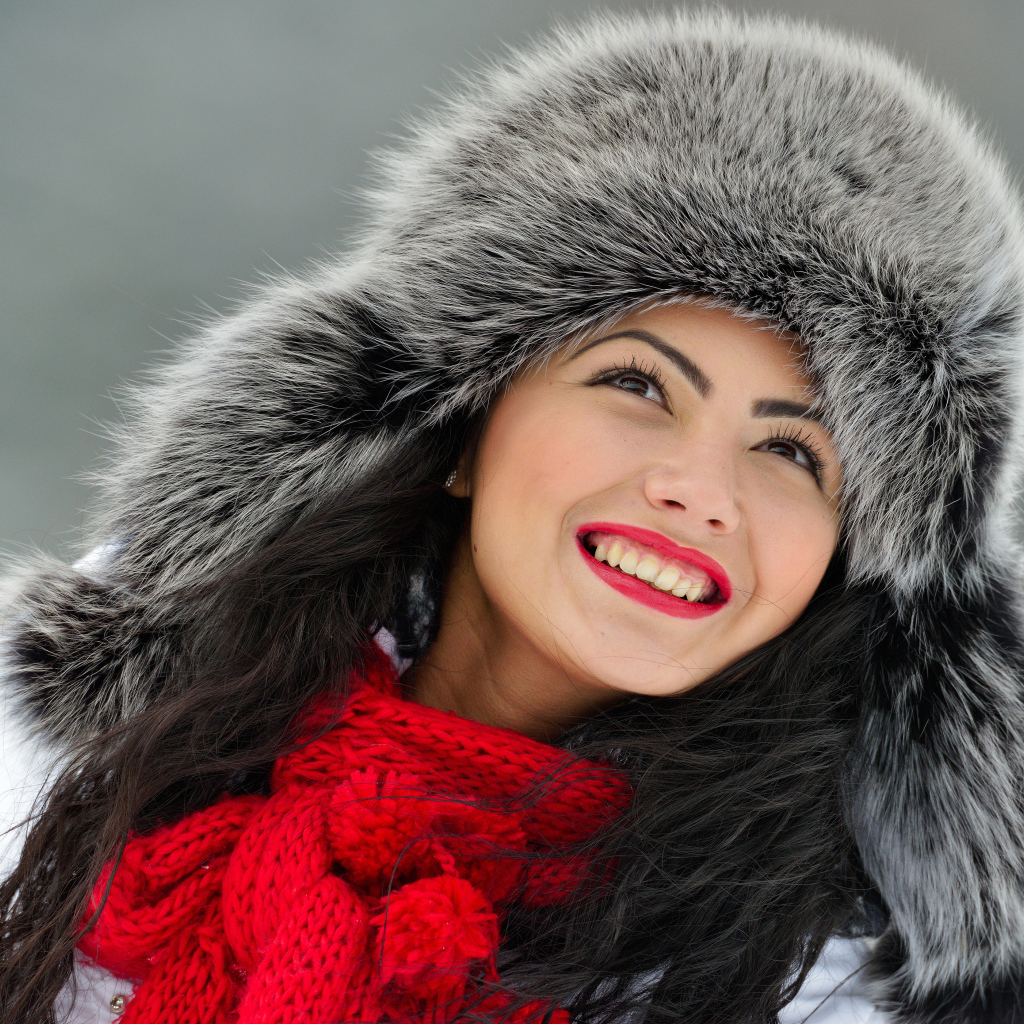 Красивая улыбающаяся брюнетка в теплой зимней шапке