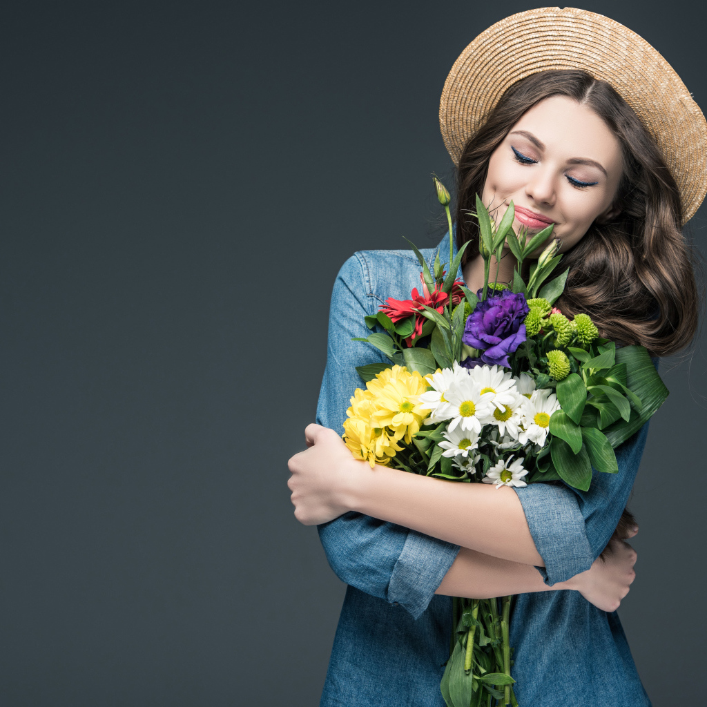 Красивая улыбающаяся девушка в шляпе с букетом цветов