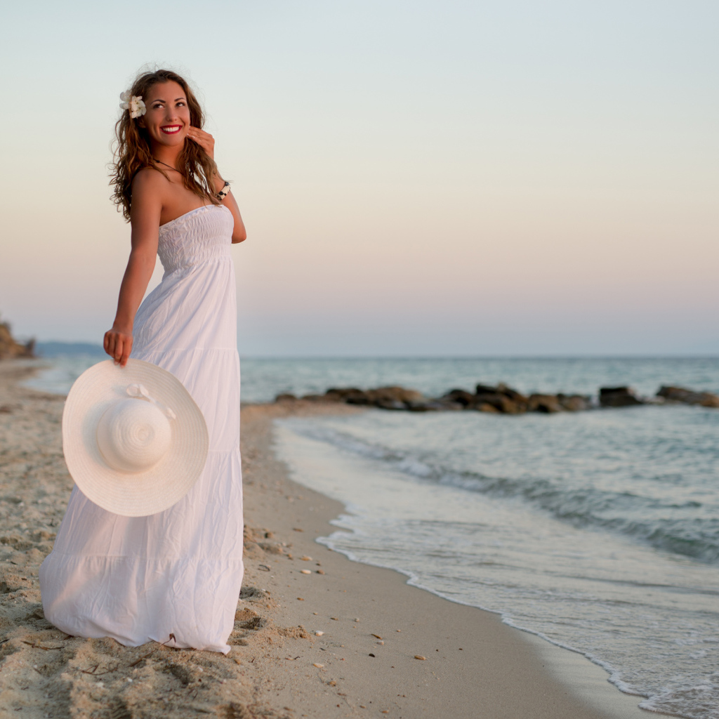 Красивая улыбающаяся девушка в белом платье на побережье