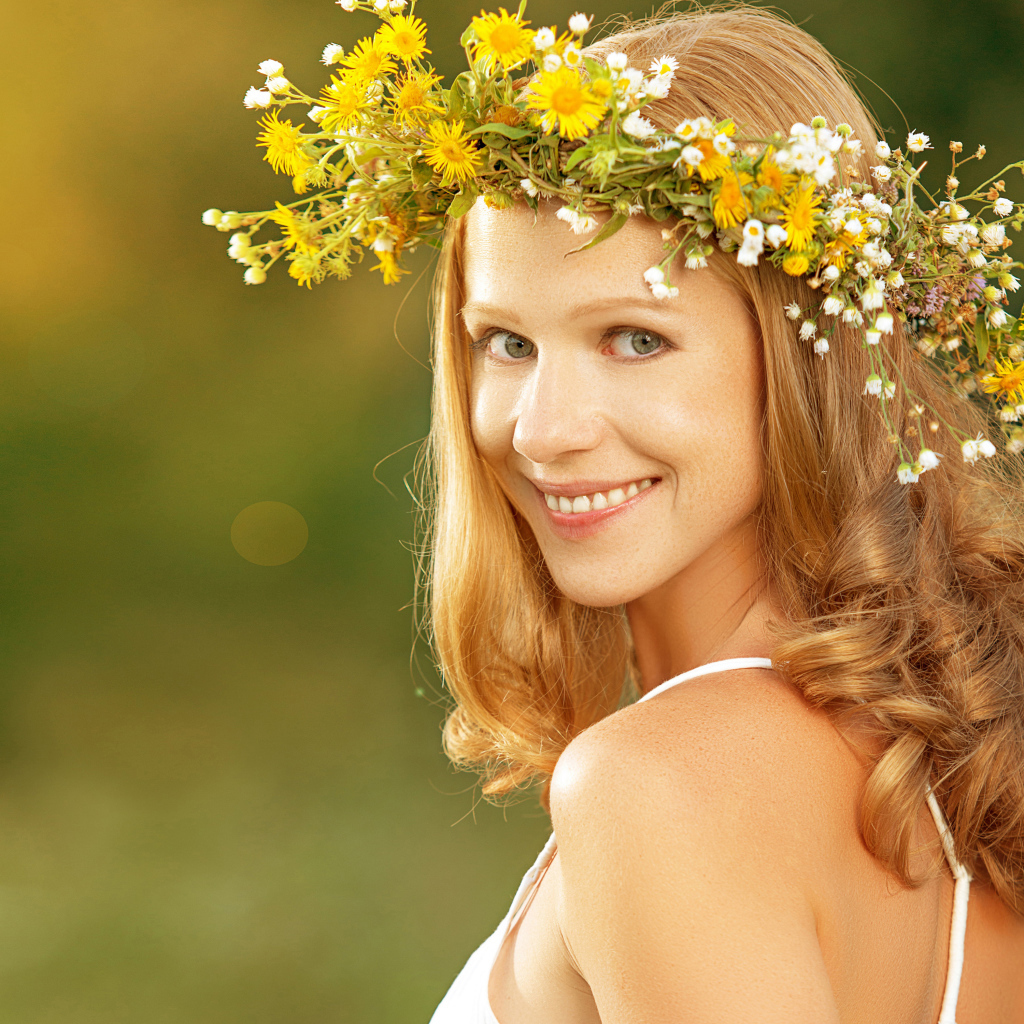 Красивая улыбающаяся девушка с венком из полевых цветов на голове