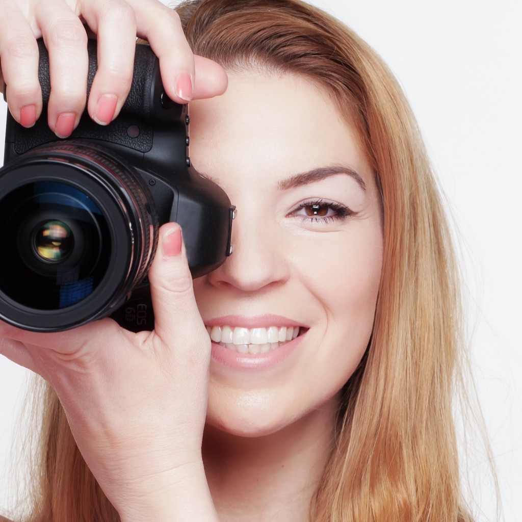 Красивая улыбающаяся девушка с фотоаппаратом