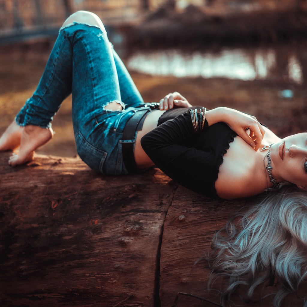 Красивая молодая блондинка лежит на сухом дереве