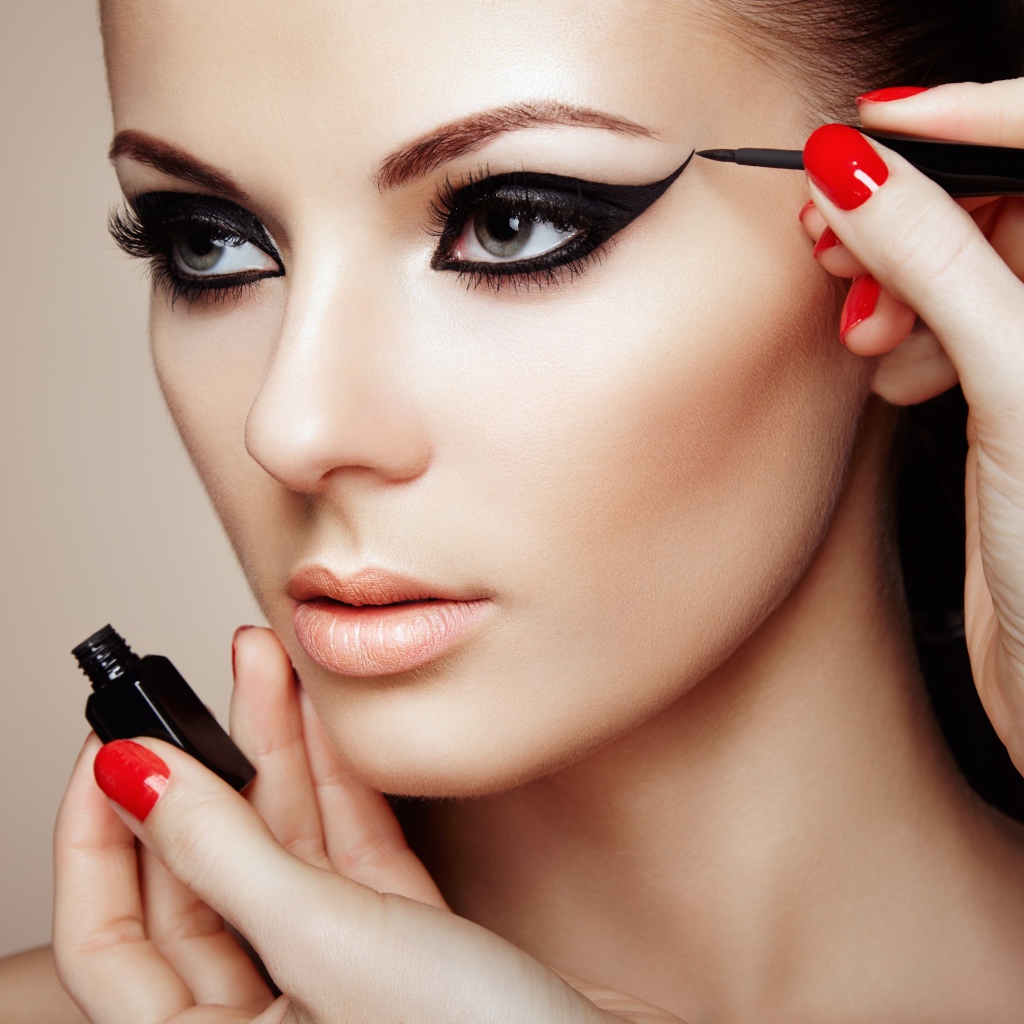 Красивой молодой девушке модели делают макияж глаз