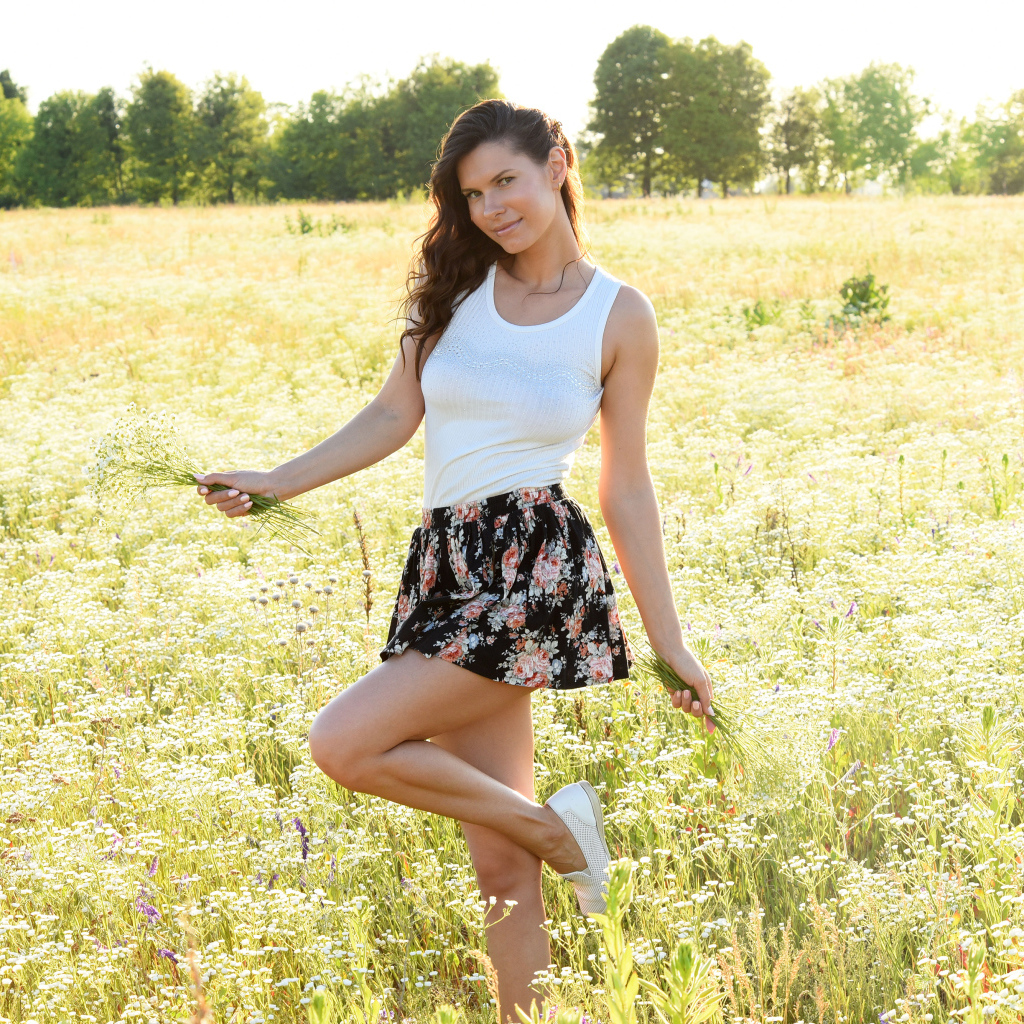 Красивая молодая девушка на поле с белыми ромашками